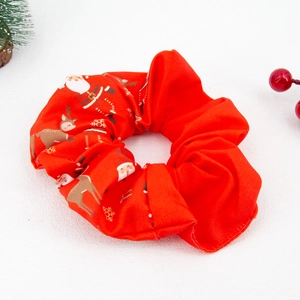 Detail of red Christmas scrunchie with Santa and reindeer prints on a festive background
