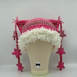 Detail of pink striped crochet cat ear hat with white faux fur trim and star tassels