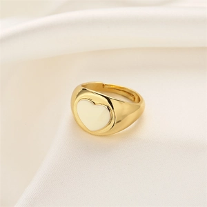 Detail of heart-shaped gold ring with white enamel finish on white silk background