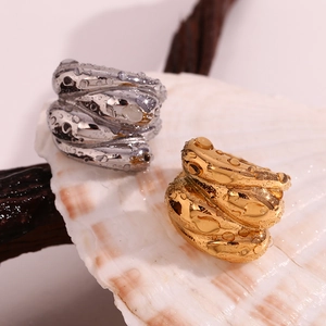 Detailed shot of gold and silver wave rings with water droplets on a seashell display