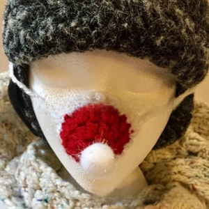 Detail of a handmade red and white knitted nose warmer with a fuzzy white pom-pom tip