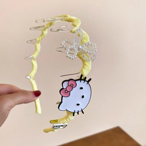 Detail of yellow fabric headband featuring cute character decor and multi-clip design