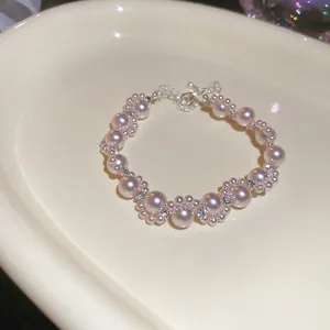Elegant French-style wrap bracelet with pink pearls and rhinestones on a ceramic tray