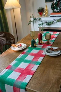 Detailed view of red and green plaid Christmas table runner with rustic cotton texture