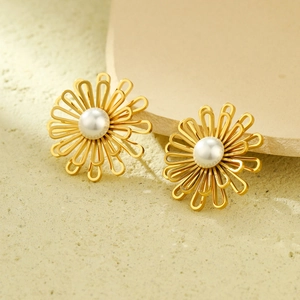 Detail view of gold floral stud earrings featuring elegant white pearls and cutout petals