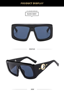Detail view of square black sunglasses with gold ring accents and gray resin lenses