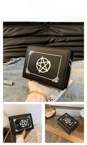 Detail of black book-shaped crossbody bag with white pentagram and gold chain strap