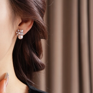 Detailed view of pink-white pearl flower stud earrings worn on a model ear