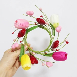Detail of tulip and heart candle ring wreath with artificial green leaves and berries