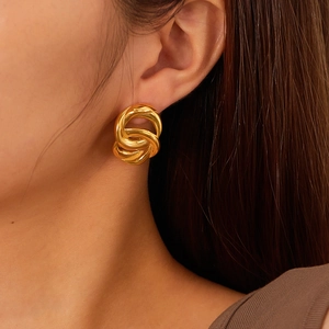 Close-up of gold-plated stainless steel earrings with twisted triple hoop design on model
