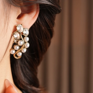 Close-up of vintage gold vine earrings with white pearls and sparkling crystals