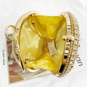 Golden round evening clutch bag with rhinestone frame and satin lining on a magazine