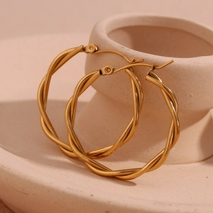 Detail of twisted 18K gold plated stainless steel hoop earrings on ceramic surface