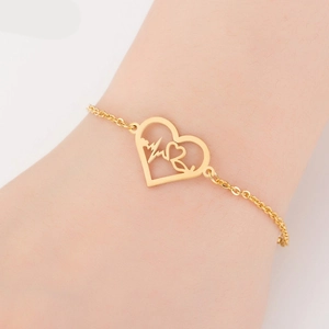 Detail of gold heart-shaped pulse bracelet on wrist showing fine chain and unique charm