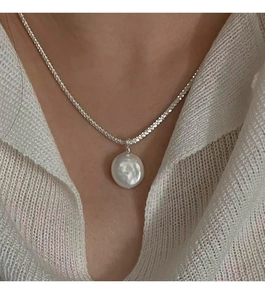 Detail of S925 silver necklace with a large white baroque pearl on a female model