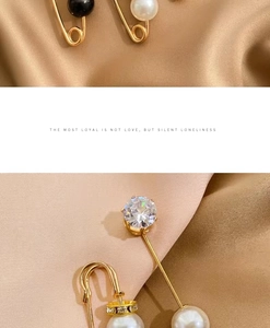 Macro view of gold safety pin brooch with pearls and round cut cubic zirconia on silk