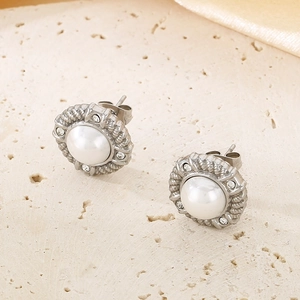 Macro shot of silver textured stud earring with center pearl and zircon accents