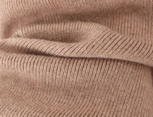 Macro shot of warm camel ribbed knit fabric detail showing soft texture and elasticity