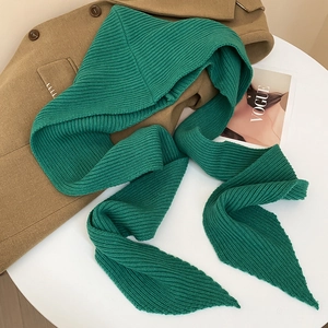 Detail of green knitted hood scarf styled on a coat with a fashion magazine