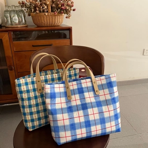 Blue plaid canvas tote bags with leather handles shown in a cozy home setting