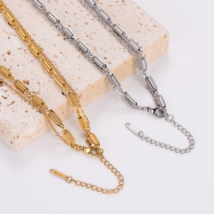 Detailed shot of gold and silver bag-shaped stainless steel pendants on a stone base