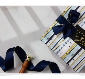 Détail du papier cadeau kraft blanc à motifs géométriques avec ruban bleu marine