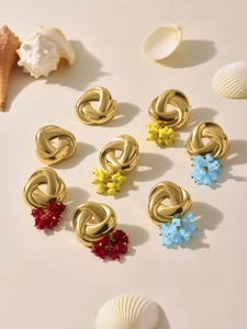 Detailed view of gold knotted earrings with colorful beaded flower clusters and sea shells