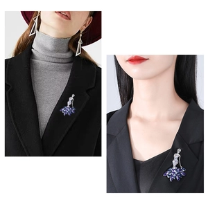 Detailed view of an elegant crystal ballet dancer brooch with dark blue stones on a coat