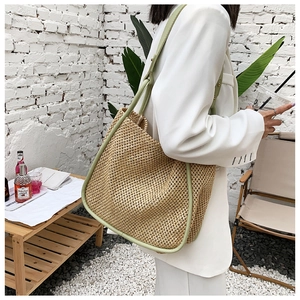 Detail of large woven straw tote bag with light green leather trim and shoulder strap