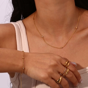 Close-up of minimalist gold jewelry set including layered necklaces and matching rings