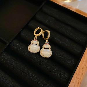 Macro shot of gold-plated gourd earrings with cat-eye stones in a black velvet box