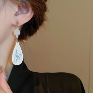 Detail of white resin floral teardrop earring worn by a model in a high-fashion pose