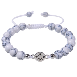 Detailed macro of white turquoise beaded bracelet with silver compass charm and braided cord
