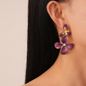 Retro purple enamel flower earrings with rhinestones on a model's ear