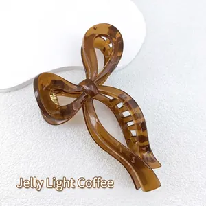 Detail of jelly caramel bow hair claw clip made of translucent resin with gold spring