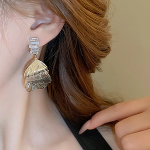 Close-up of silver-tone hollow petal earrings with zircons worn by a model