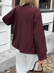 Outdoor shot showing the back view of a loose burgundy women's casual jacket with buttons