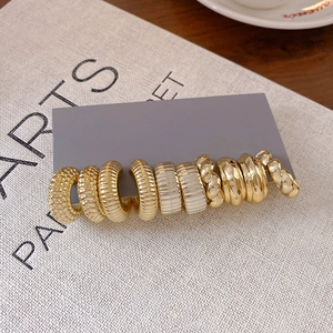 Assorted gold oval C-shape hoop earrings with diverse textures on a display card