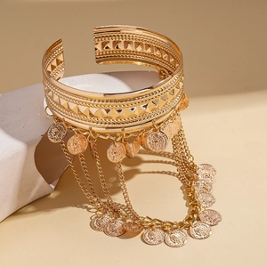 Detail of vintage gold coin tassel arm cuff with layered chains on geometric display