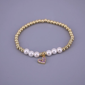 Detail of beaded bracelet with gold beads, white pearls, and purple zircon heart charm