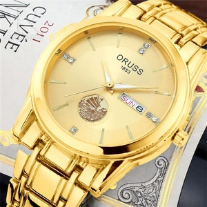 Macro shot of gold stainless steel watch dial with sailboat logo and day-date display