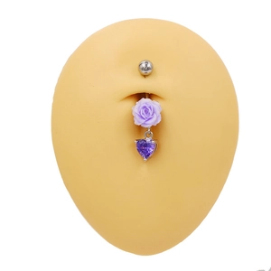 Détail du piercing de nombril argenté avec rose violette et pendentif cœur sur modèle