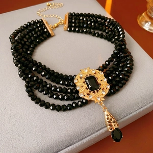 Macro view of five-strand black beaded choker with vintage gold pendant and black gemstone