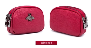 Macro detail of wine red pebbled leather coin purse with triple zipper and bee accent