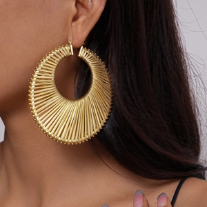 Close-up of bohemian gold woven geometric hoop earrings worn by a model