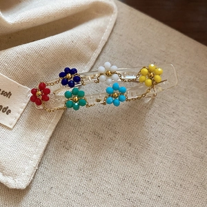 Detailed close-up of a floral hair clip with six colorful beaded flowers and golden chains