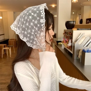 Detail of white floral lace triangle headscarf with delicate scalloped edges in cafe setting
