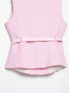 Vue macro du tissu en tweed rose et détail de la boucle de taille sur la veste
