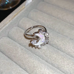 Macro shot of silver crescent moon ring with sparkling zircon and small pearls