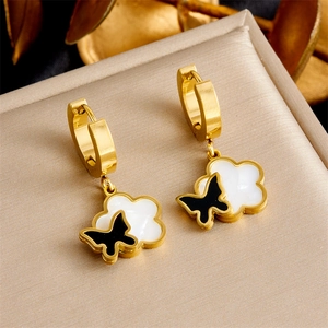 Detailed macro view of gold-plated hoop earrings featuring white cloud and black butterfly charms